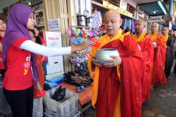 Une employée d’un magasin musulman donne l’aumône à des moines bouddhistes à Magelang, au centre de l’île de Java, le 16 mai 2011, à la veille de la fête de Vesak, qui commémore la naissance, l’illumination et la mort de Bouddha. (Crédit : AFP PHOTO / CLARA PRIMA)